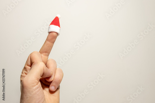 Obraz na plátně The middle finger of a man's hand with a Santa Claus hat