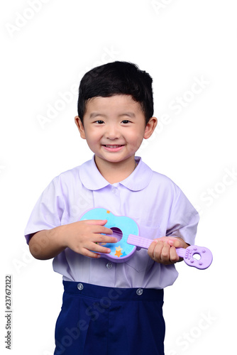 Asian Thai kindergarten student kid in school uniform playing toy guitar isolated on white background with clipping path. musical concept