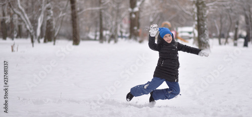 a child in winter clothes jumping on the snow