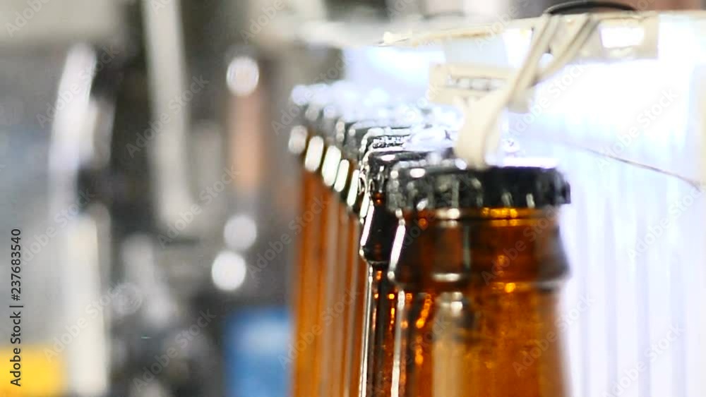 Brewery concept. Beer factory. Automatic Beer Bottling Line. Closeup shot of Queue of ready filled bottles on the conveyer. 4k Brewery concept. Beer factory. Automatic Beer Bottling Line. Closeup shot of Queue of ready filled bottles on the conveyer. 4k