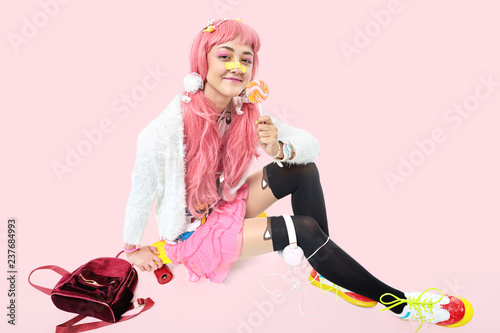 Tableau sur toile A beautiful Asian teen girl in pink headphones, dressed in anime or kawaii style