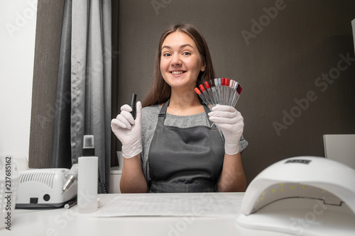 happy  young woman profession manicurist with polish and nail color palette