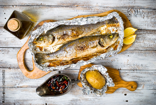 Fresh baked fish sea bass (Dicentrarchus labrax) on a light wooden background