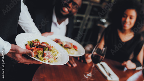 Waiter Serving Salad to African Couple Restaurant