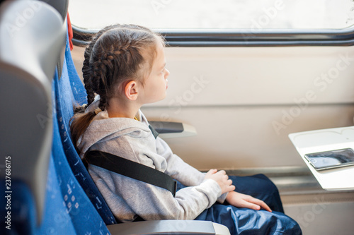 Little girl sitting by the window in the train