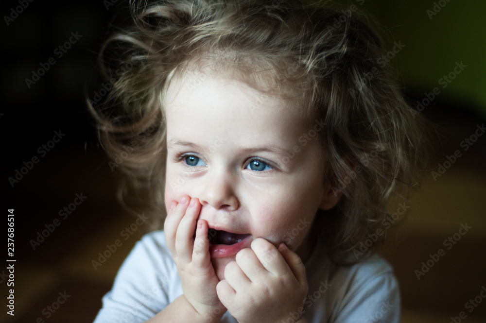 Closeup portrait of a child. Surprised, she raised her hands to her mouth. Shaggy girl. Emotional concept Closeup portrait of a child. Surprised, she raised her hands to her mouth. Shaggy girl. Emotional concept