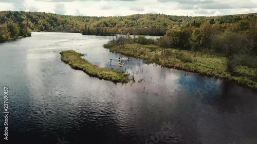 Gliding drone schene zooming in on a group of kayakers paddling upstream in the wilderness. photo