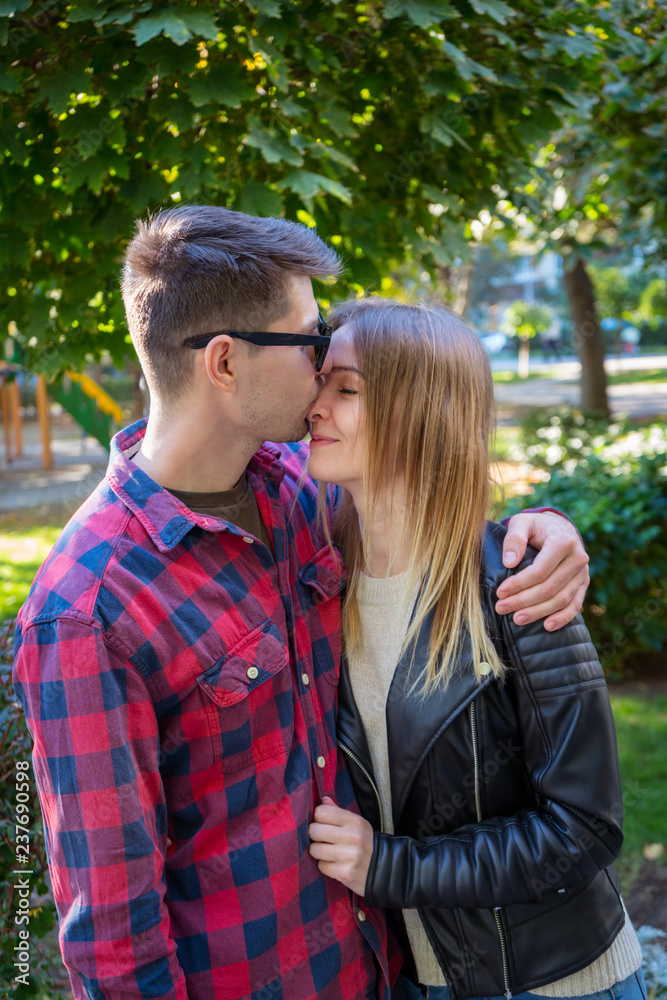 Fototapeta premium A man hugs a girl in the park. Man in plaid shirt. Couple in love