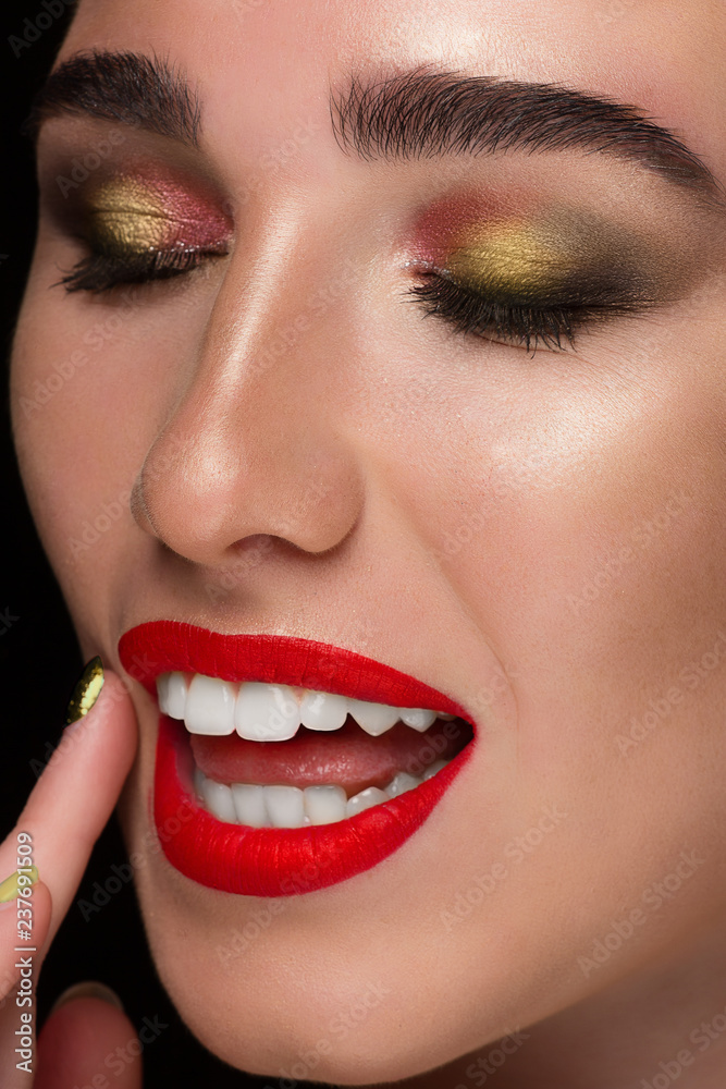 Close up beauty portrait of young woman with beautiful summer bright makeup. Modern smokey eyes with colorful metallic eyeshadows and red lipstick. Studio shot white smile with teeth Close up beauty portrait of young woman with beautiful summer bright makeup. Modern smokey eyes with colorful metallic eyeshadows and red lipstick. Studio shot white smile with teeth