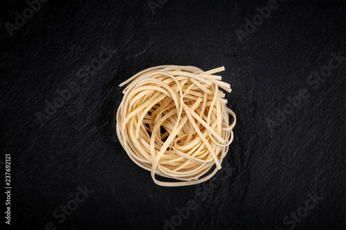 A photo of udon noodles in the form of a nest, shot from the top on a black background with a place for text