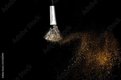 golden powder splash and brush for makeup artist or beauty blogger in black background