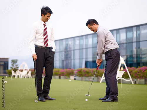 asian corporate executives playing golf on rooftop court
