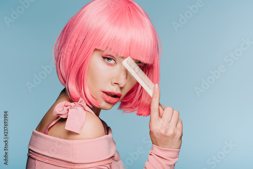 beautiful stylish girl in pink wig posing with hair comb isolated on blue photo