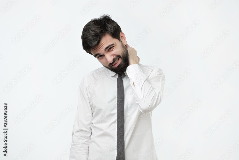 I need a massage. Frustrated mature spanish man in white shirt holding hand on his neck while standing against grey background I need a massage. Frustrated mature spanish man in white shirt holding hand on his neck while standing against grey background