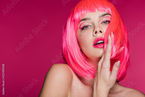 beautiful sensual young woman posing in neon pink wig, isolated on pink