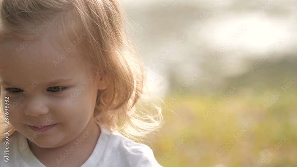 Portrait of smiling baby with soap bubbles looking at the camera in the summer park in sunset light. Portrait of smiling baby with soap bubbles looking at the camera in the summer park in sunset light.