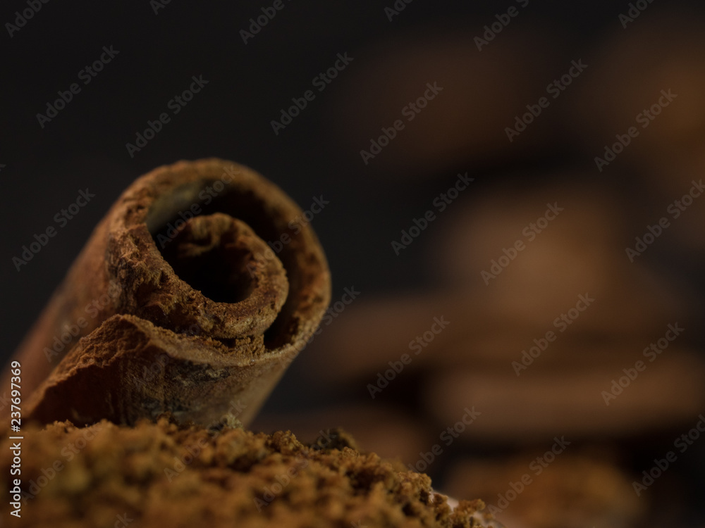 stick of cinnamon with a vintage spoon of ground coffee. coffee with spices. Food background on dark stone table. Macro close-up image.