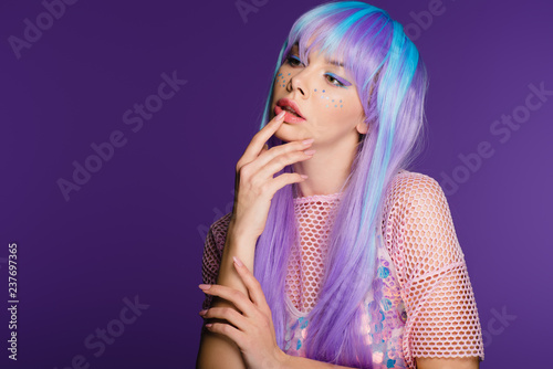 attractive woman posing in violet wig with stars on face, isolated on purple © LIGHTFIELD STUDIOS