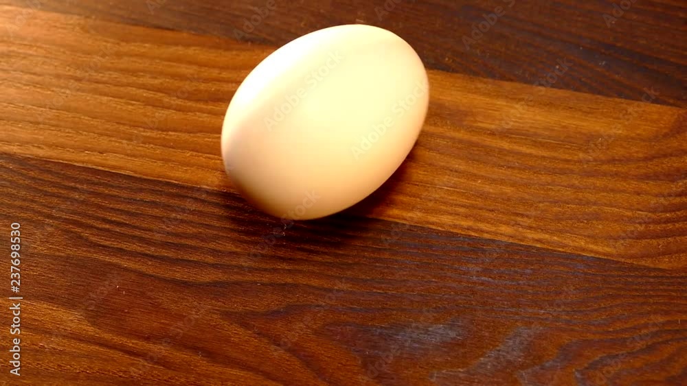 Chicken egg is spinning on the kitchen table. Boiled or raw egg unwound by hand. Chicken egg is spinning on the kitchen table. Boiled or raw egg unwound by hand.