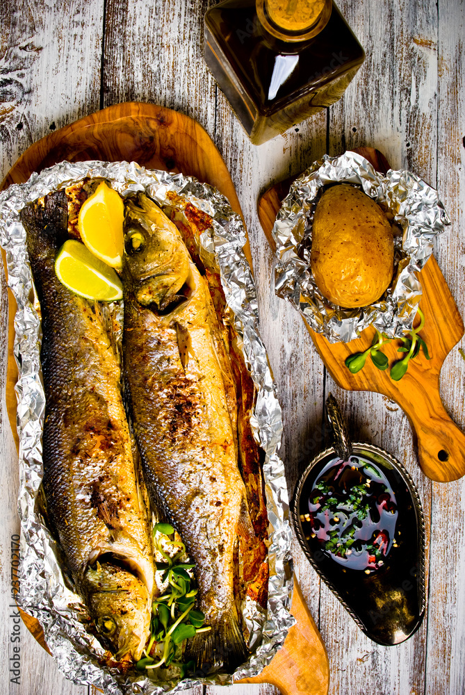 Fresh baked fish sea bass (Dicentrarchus labrax) on a light wooden background