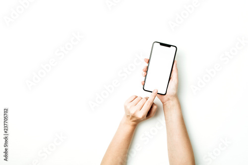 Woman touching blank screen of new model of smart phone on white background. Flat lay, top view mockup.