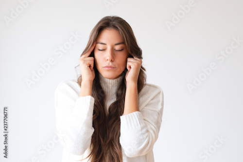 Attractive tired girl touching painful temples. Portrait of young Hispanic woman with closed eyes having headache. Isolated on white. Relaxing concept