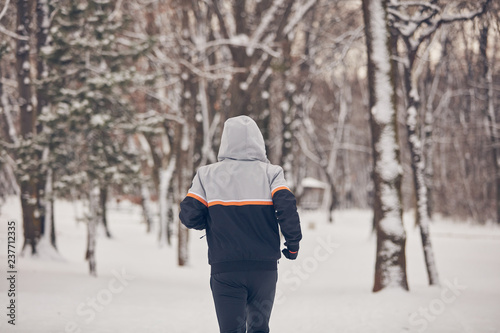 Man jogging in a cold winter snowy day outdoors.