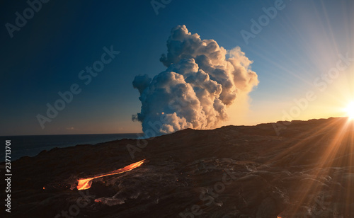 Kilaulea volcano lawa flow, steam cloud rising from ocean at sunset time