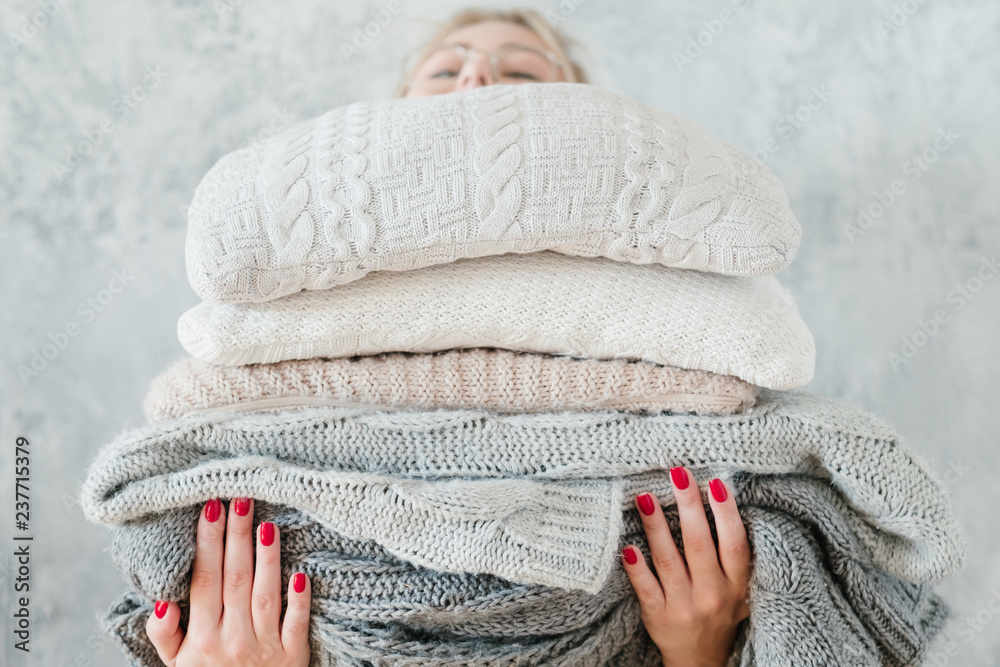 woman holding big stack of knitted plaids and blankets. cozy and warm winter home decor - obrazy, fototapety, plakaty 