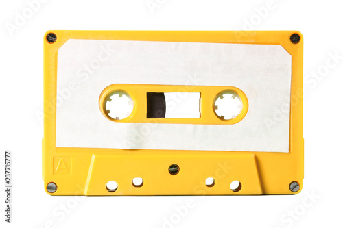An old vintage cassette tape from the 1980s (obsolete music technology). Electro yellow plastic body, white paper label, isolated. 