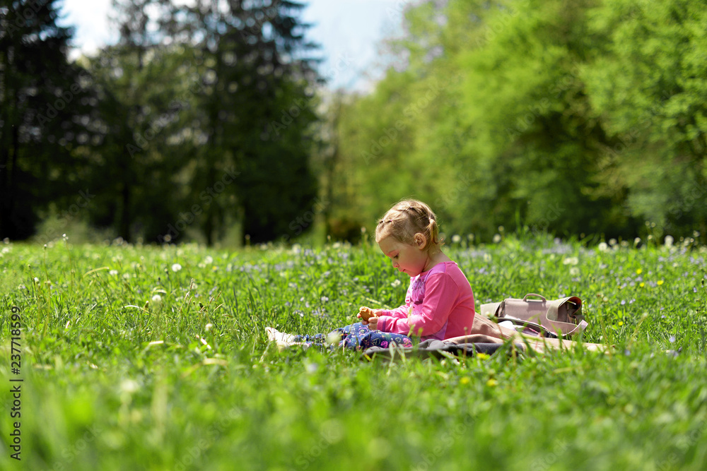 Little girl resting on a green meadow among meadow flowers in the warm spring Little girl resting on a green meadow among meadow flowers in the warm spring