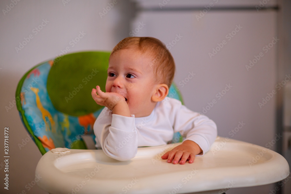 Child Feeding. cheerful boy sitting on the highchair.. Child Feeding. cheerful boy sitting on the highchair..