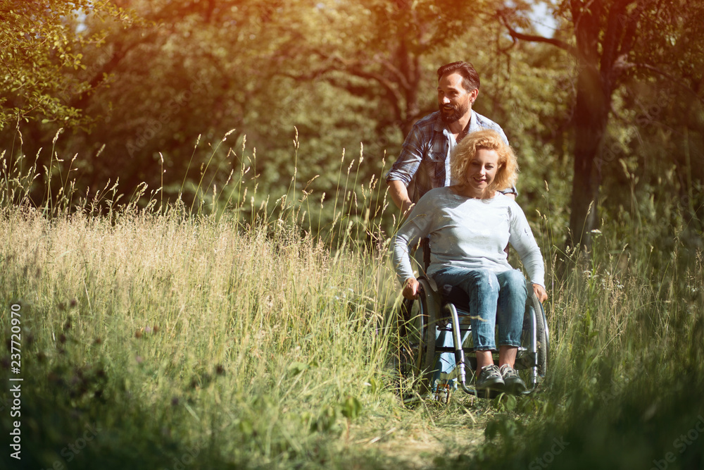 Happy woman in wheelchair with her husband. Outdoors Happy woman in wheelchair with her husband. Outdoors