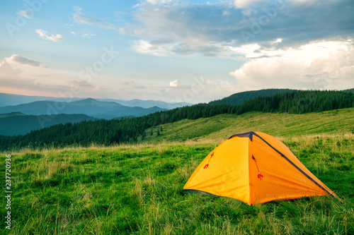 Orange tourist tent in green mountains