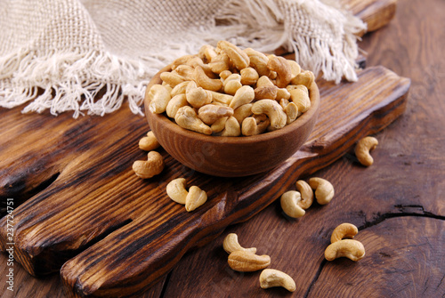 Fried cashew in a bowl on a dark wooden background.