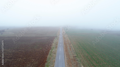 Aerial view on speed road, partly covered by fog. Vertical view on rural countryside in autumn, foggy morning. Misty empty road.