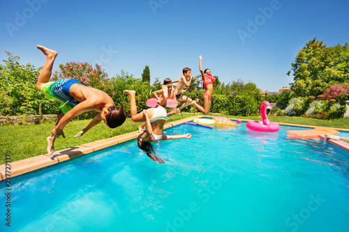 Happy friends doing front flip in swimming pool