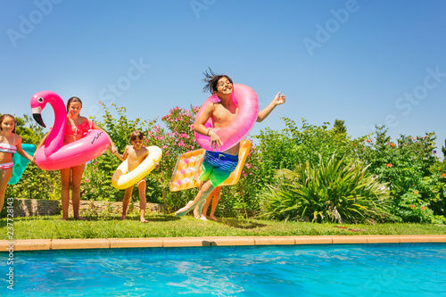 Boy in swim ring playing pool games with friends