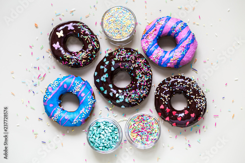 homemade doughnuts with colored frosting and different sprinkles on white background