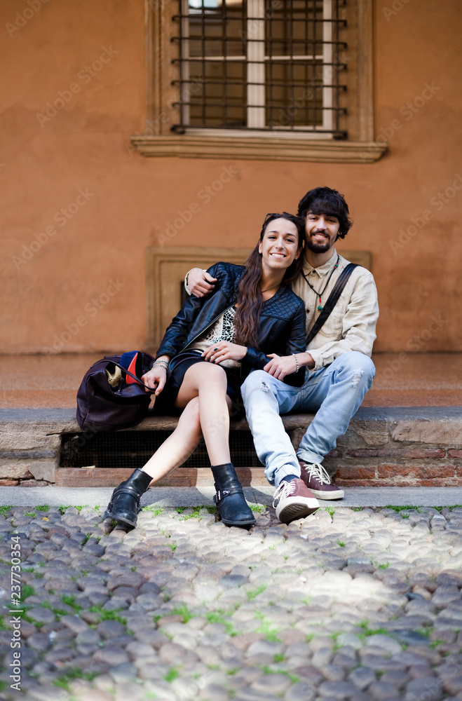 Portrait of happy young couple sitting on steps outdoors