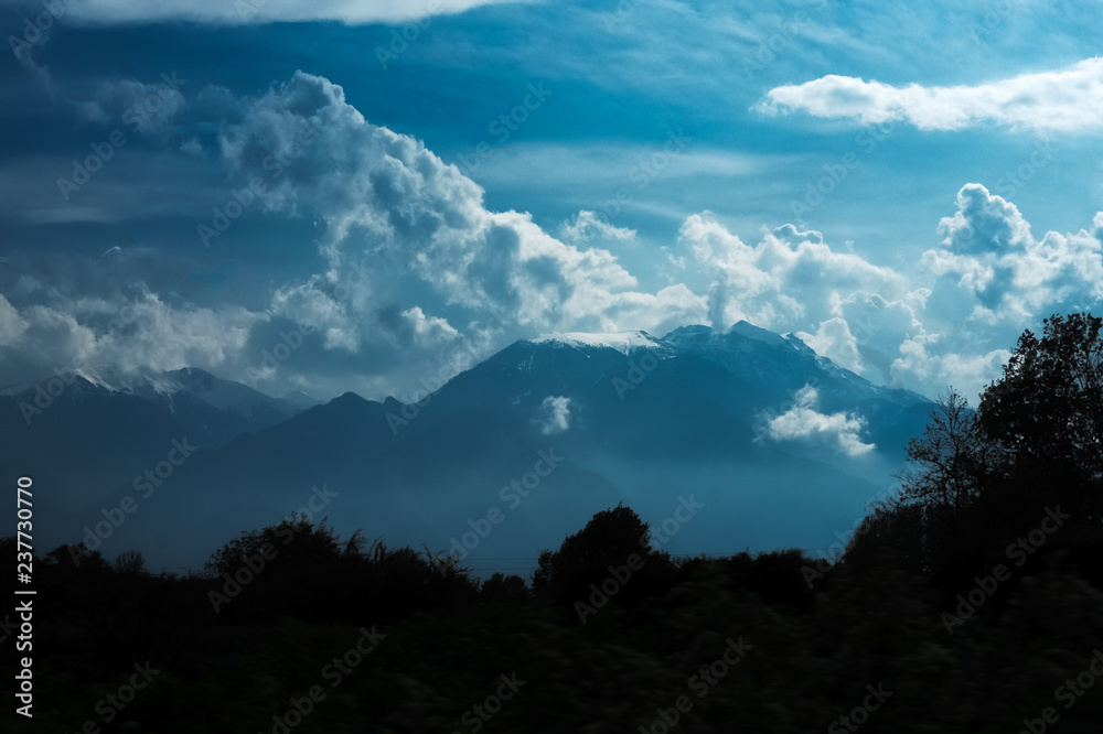 Dramatic landscape of peak mountains with clouds and sunlight.