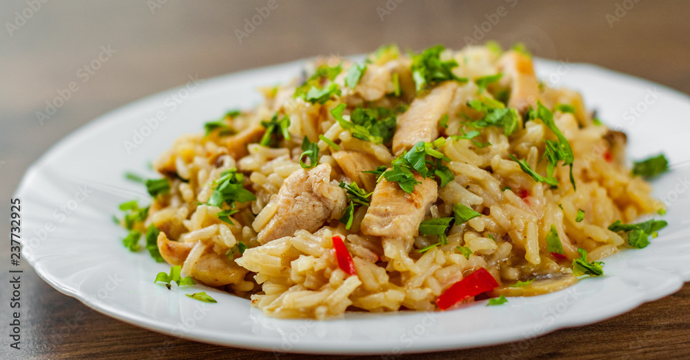 Chicken Breast with Rice, mushroom and vegetables in white plate on wooden table background Chicken Breast with Rice, mushroom and vegetables in white plate on wooden table background