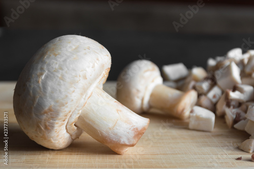 Mushrooms champignon on rustic background. Deep shadows. Side view. Food photography concept.