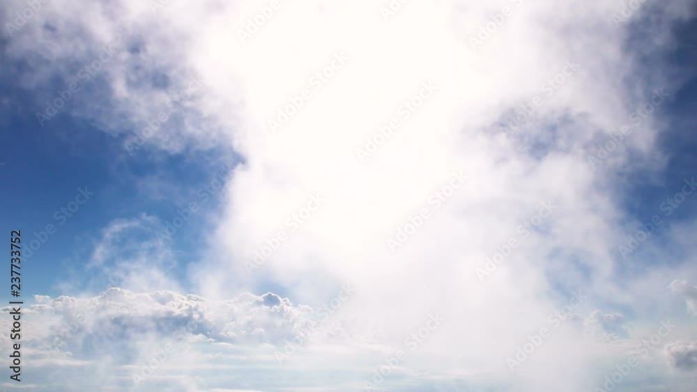 White flufly clouds passing blue sky with bright sun shining