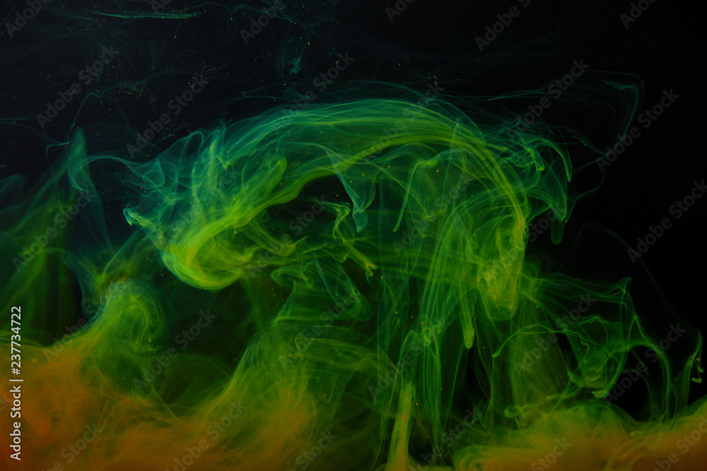 Obraz premium black background with abstract green and orange swirls of paint