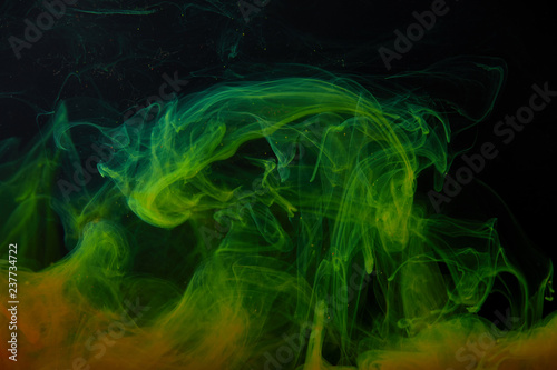 black background with abstract green and orange swirls of paint © LIGHTFIELD STUDIOS