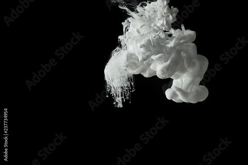 white paint splash flowing in water on black background