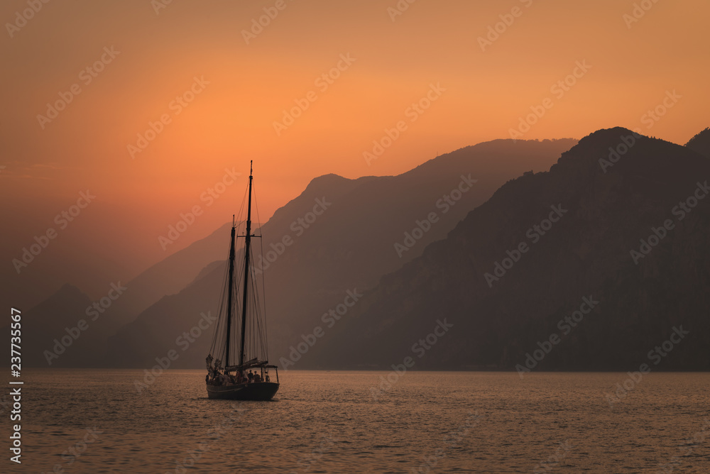 Sailboat sailing at sunset on the background of a mountain range. Traveling  inspiration concept