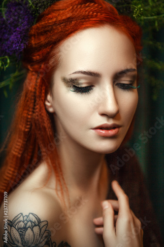 Young red head model is posing with a creative makeup 