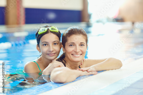 The daughter and mother swim in the swimming pool